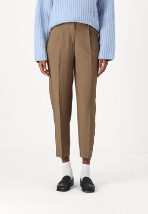 Pantalons ajustés marron avec une coupe droite, détail de plis et poches latérales, associés à un pull en maille bleu clair et des mocassins noirs.