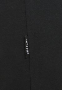 Black cotton t-shirt with a textured surface and a side tag displaying "ONLY & SONS" in white lettering. Simple, unembellished design.