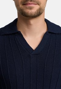 Marineblauer Strickpullover mit V-Ausschnitt und strukturiertem Rippmuster. Verfügt über einen klassischen Kragen und ein weiches Material.