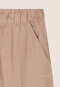 Pantalones de tela liviana en color rosa claro, con cinturilla elástica, bolsillo lateral y logo bordado de "Freddy" en el costado inferior.