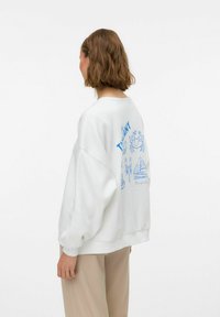 Sudadera blanca con diseños gráficos azules que presentan un cangrejo, un velero y texto, con mangas oversize y un ajuste relajado.