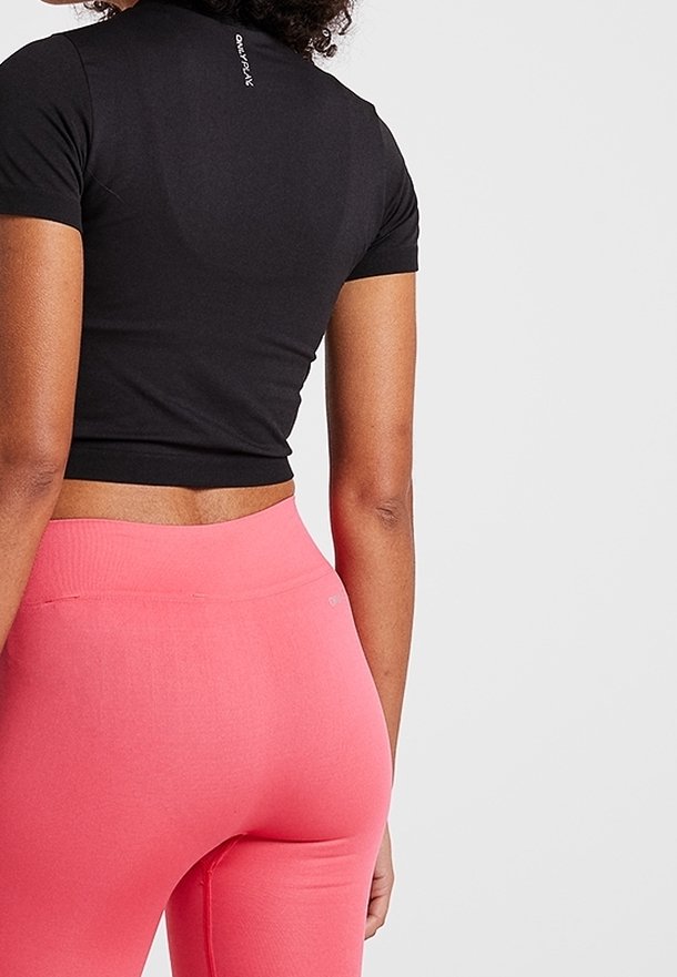 Černé crop tričko s přiléhavými krátkými rukávy, doplněné růžovými legínami s vysokým pasem, které mají hladkou texturu a minimalistický design.