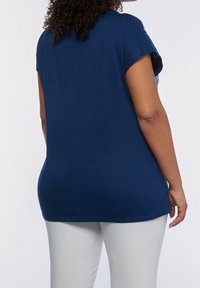 Marinblå kortärmad topp med rund halsringning, avslappnad passform och en mjuk bomullstextur. Sömmen slutar strax under höfterna.