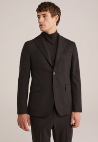 Dunkelgrauer maßgeschneiderter Blazer mit Reverskragen, zwei vorderen Taschen und Ein-Knopf-Verschluss. Der Stoff ist glatt und hat ein strukturiertes Design.