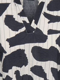 Tissu blanc à fines rayures verticales avec de grandes formes abstraites noires irrégulières formant un motif texturé.