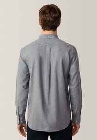 Grijze overhemden met lange mouwen, gemaakt van een gestructureerde stof. Bevat een achterste schouderstuk en barrel cuffs met witte knopen.