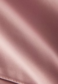 Weiches rosa Gewebe mit feiner gerippter Struktur, das glatte Fasern und einen subtilen Glanz zeigt, geeignet für Bekleidung oder Polsterung.