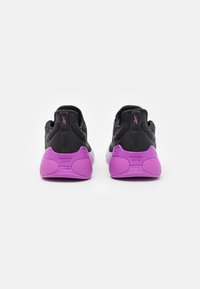 Par de zapatillas deportivas negras y moradas vistas desde atrás con el texto "NANO GYM" en los contrafuertes morados contra un fondo blanco.