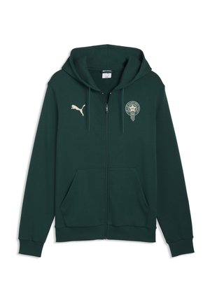 Mørkegrøn lynlåshoodie med forlommer, Puma-logo på venstre bryst og cirkulært emblem med arabisk tekst på højre bryst.