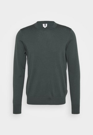 Maglione verde scuro a maniche lunghe con scollo rotondo e polsini e orlo a coste, mostrato su uno sfondo chiaro uniforme.