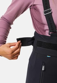 Zwarte skibroek met verstelbare klittenband tailleband en ritssluitingdetails. Heeft een accent van de Zweedse vlag. Stof lijkt glad met een slim fit ontwerp.