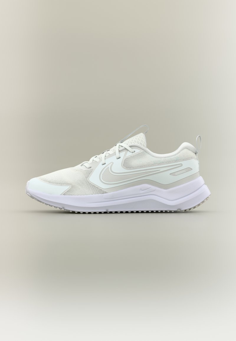 Zapatilla deportiva blanca con parte superior de malla, superposiciones texturizadas, una entresuela acolchada y una suela de goma con pequeños tacos de tracción.