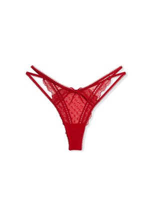Culotte string en dentelle rouge avec double bandeau à la taille, tissu transparent à pois, bords ondulés et petit nœud au centre devant.