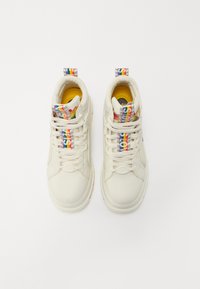 Zapatillas altas de cuero blanco con un acabado texturizado. Cordones de colores y un forro amarillo, con un logo en el costado.