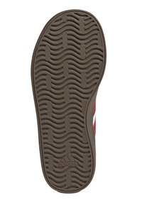 Suela de un zapato con un patrón texturizado en forma de ondas, principalmente marrón con zonas de gris claro; marcada con "adidas" en el centro.