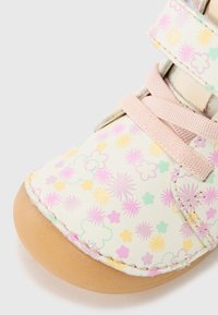 Hvit støvel med gummisåle. Har et blomstermønster i rosa, gul og mintgrønn. Inkluderer rosa stropper for lukking.