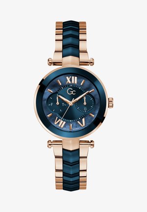 Reloj de pulsera de oro rosa con esfera azul marino, números romanos y dos subesferas. Presenta una correa texturizada con eslabones metálicos y azules alternos.