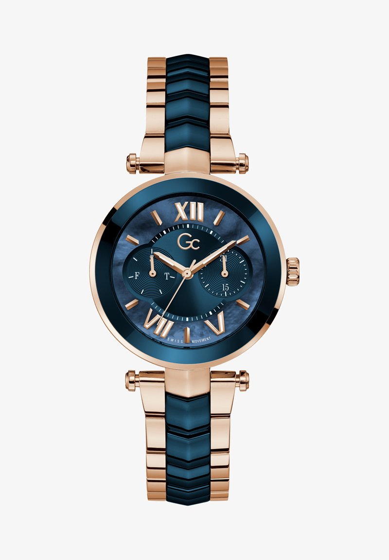 Orologio da polso rosa gold con quadrante blu navy, numeri romani e due sottodial. Presenta un bracciale testurizzato con link metallici e blu navy alternativi.