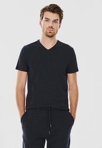 Czarny krótki rękaw V-neck t-shirt wykonany z miękkiej bawełny, cechujący się dopasowanym krojem i komfortową teksturą, w połączeniu z czarnymi spodniami dresowymi.