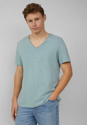 Hellblaues V-Ausschnitt-T-Shirt aus weichem Stoff, mit kurzen Ärmeln und lockerer Passform. Kombiniert mit verwaschenen blauen Denim-Jeans.