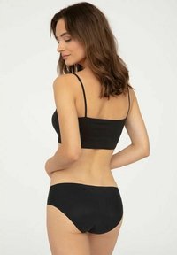 Czarny biustonosz i pasujące figi bikini. Materiał jest gładki z minimalną ilością szwów. Fiszbina ma cienkie ramiączka i prosty design.