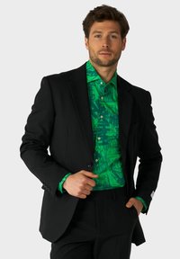 Čierna sako s jasne zelenou vzorovanou košeľou, ktorá obsahuje jedinečný grafický dizajn. Na košeli sú viditeľné nápadné gombíky.