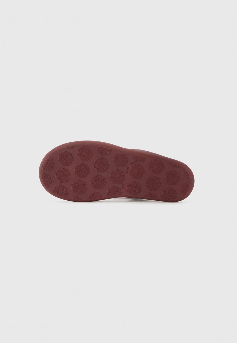 Suela de zapato de goma en burdeos con una superficie texturizada que presenta patrones hexagonales para un mejor agarre. Bordes suaves y forma ligeramente curvada.