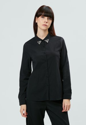 Camisa negra de manga larga con botones en el frente y un collar adornado con detalles decorativos. Fabricada en tejido suave con un corte entallado.