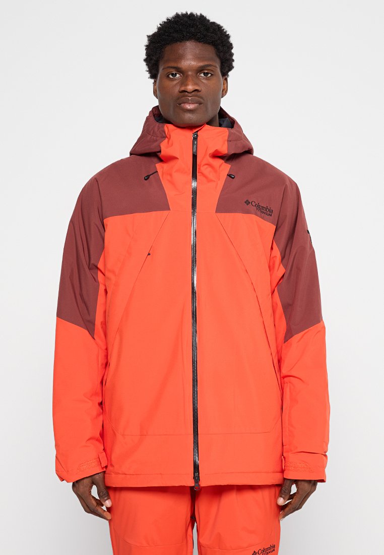 Columbia wasserdichte Jacke, leuchtend orange mit dunkelbraunen Akzenten. Sie verfügt über einen Frontreißverschluss, eine verstellbare Kapuze und ein lässiges Design.