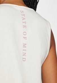 Lysegrå ærmeløs top med teksten "STATE OF MIND" i pink på ryggen. Glat stof med en afslappet pasform og rundet halsudskæring.