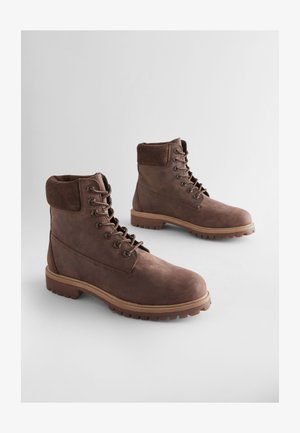 Braune Leder-Stiefeletten mit strukturierter Oberfläche, gepolstertem Schaft, Metallösen und robustem Gummisohlen. Stilvolles Design für Langlebigkeit.