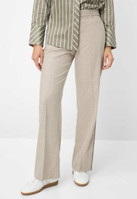 Beige wijde broek met een hoog waist en zijstrepen, gemaakt van gestructureerde stof, gecombineerd met witte sneakers.