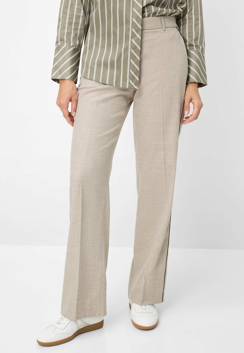 Beige wijde broek met een hoog waist en zijstrepen, gemaakt van gestructureerde stof, gecombineerd met witte sneakers.