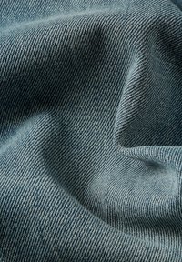 Tecido de denim azul claro com um padrão de sarja, apresentando uma textura subtil e um acabamento suave, amassado e drapeado em suaves pregas.