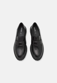 Scarpe slip-on in pelle nera con finitura liscia, punta rotonda e suola in gomma cucita con un leggero tacco.