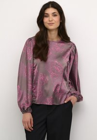 Satin blouse in grey with pink floral print, featuring long sleeves, gathered shoulders, and a loose fit. Paired with dark pants.
