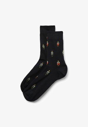 Marineblaue Socken mit einem wiederholten Nussknacker-Muster in Rot, Gelb und Grün. Glatte Textur, Standard-Knipshöhe und verstärkte Spitze.