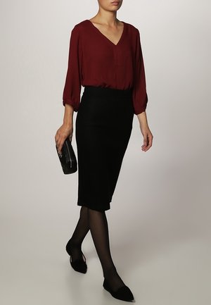 Blouse bordeaux à col en V et manches froncées, assortie d'une jupe crayon noire ajustée, de collants noirs et de ballerines noires. Accessoirisée avec une pochette.