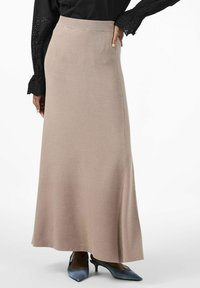 Lång beige stickad kjol med en mjuk textur och lätt utsvängning i fållen, tillsammans med ljusblå klackar. Topp med volangärm i svart.