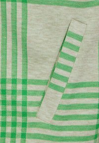 Textil verde y beige con un patrón a cuadros y rayas, que incluye un bolsillo de parche texturizado en el lado izquierdo.