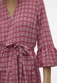 Rozā rakstaina apģērba kleita ar ģeometrisku dizainu, ar platām piedurknēm un sasietu jostas detaļu, izgatavota no viegla auduma.