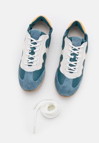 Sneakers with a teal and white upper, suede and leather materials, lace-up design, rounded toe, and a gum sole. Includes white laces.