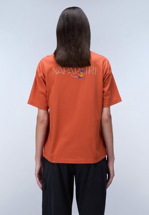 Oranje katoenen t-shirt met korte mouwen, voorzien van het 'NAPAPIJRI' logo en een grafisch ontwerp op de achterkant. Relaxte pasvorm met een ronde halslijn.