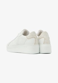 Weiße Leder-Sneaker mit einem strukturierten Cremeton-Akzent an der Ferse, flacher weißer Sohle und tonal abgestimmter Naht. Minimalistisches Design und abgerundete Form.