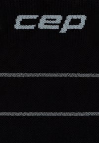 Calcetines negros con una textura suave, que presentan un logo gris "CEP" y una franja horizontal gris en el centro.