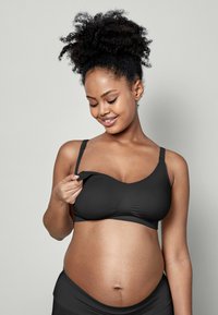 Schwarzer Still-BH mit verstellbaren Trägern, glattem Stoff und einem Öffnungsbereich vorne für das Stillen. Mit sanften Kurven und subtilen Nahtdetails.