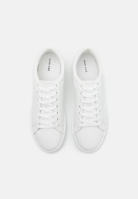 White sneakers with a smooth leather exterior, round-toe design, six eyelets, and flat laces, featuring subtle branding on the insole.