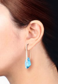 Silver hoopörhängen med en stor, facetterad blå kristallhänge, designade med en minimalistisk, modern estetik och slät yta.