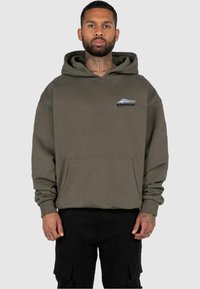 Felpa color khaki con tasca frontale, caratterizzata da un piccolo logo grafico blu e nero. Morbido al tatto e con una vestibilità comoda.