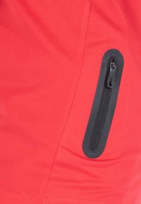 Rode stoffen zak met een zwarte rits en afwerking. Glad textuur met een lichte rek. Beschikt over strakke lijnen en een minimalistisch ontwerp.